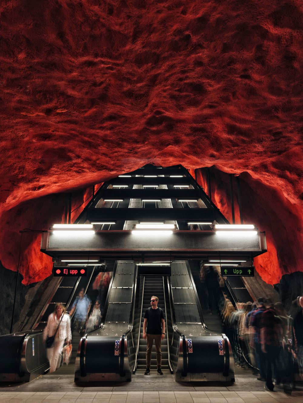 a group of people standing in front of an escalator