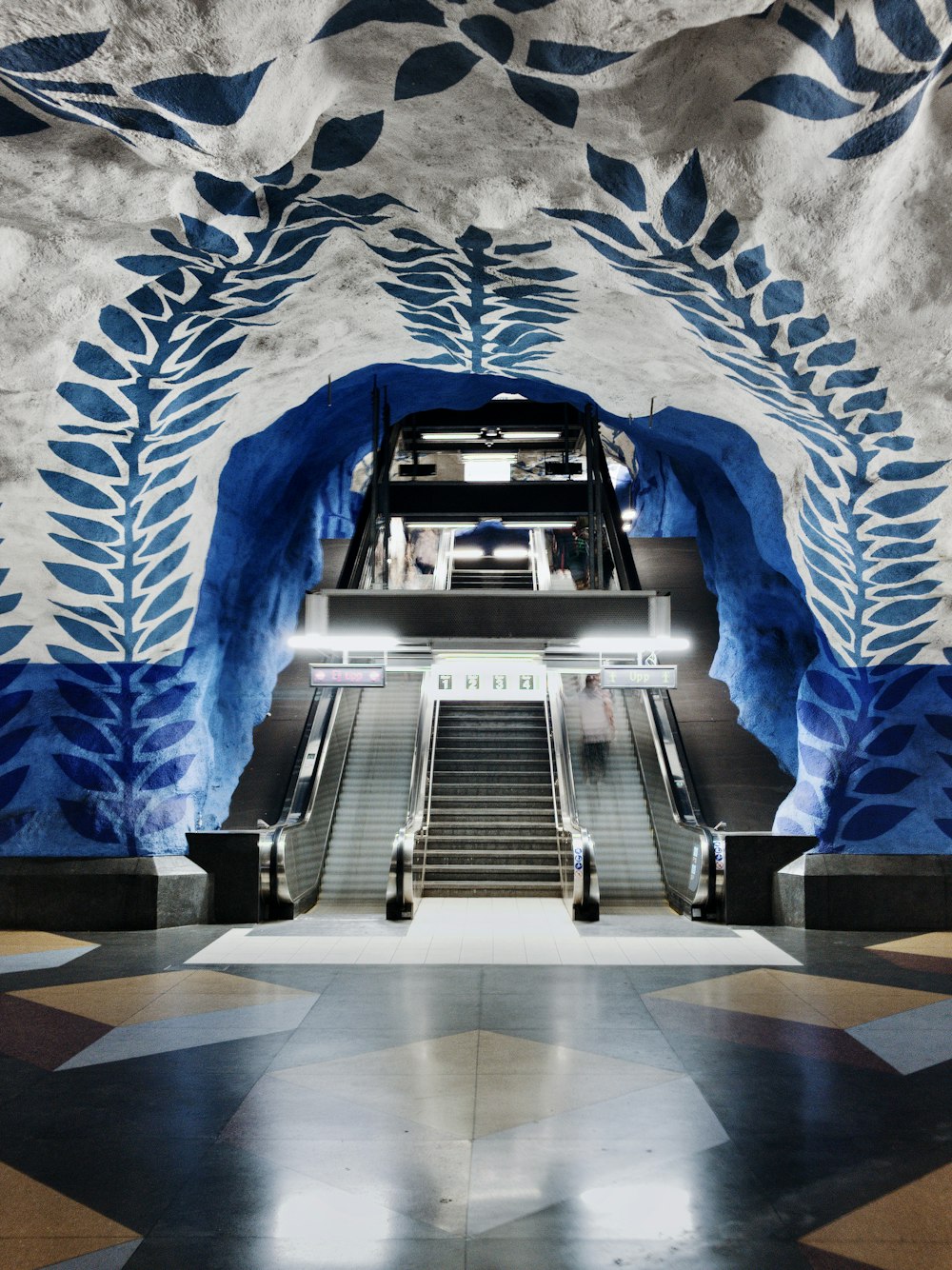 an escalator in a building with a mural on the wall