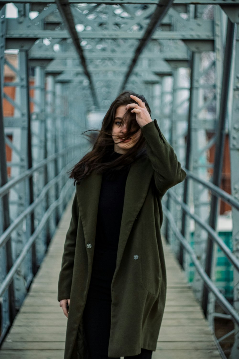 a woman standing on a bridge with her hair blowing in the wind