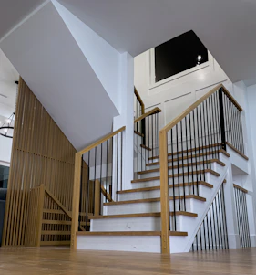 A beautifully crafted modern wooden staircase with sleek metal railings in a bright, airy home interior.