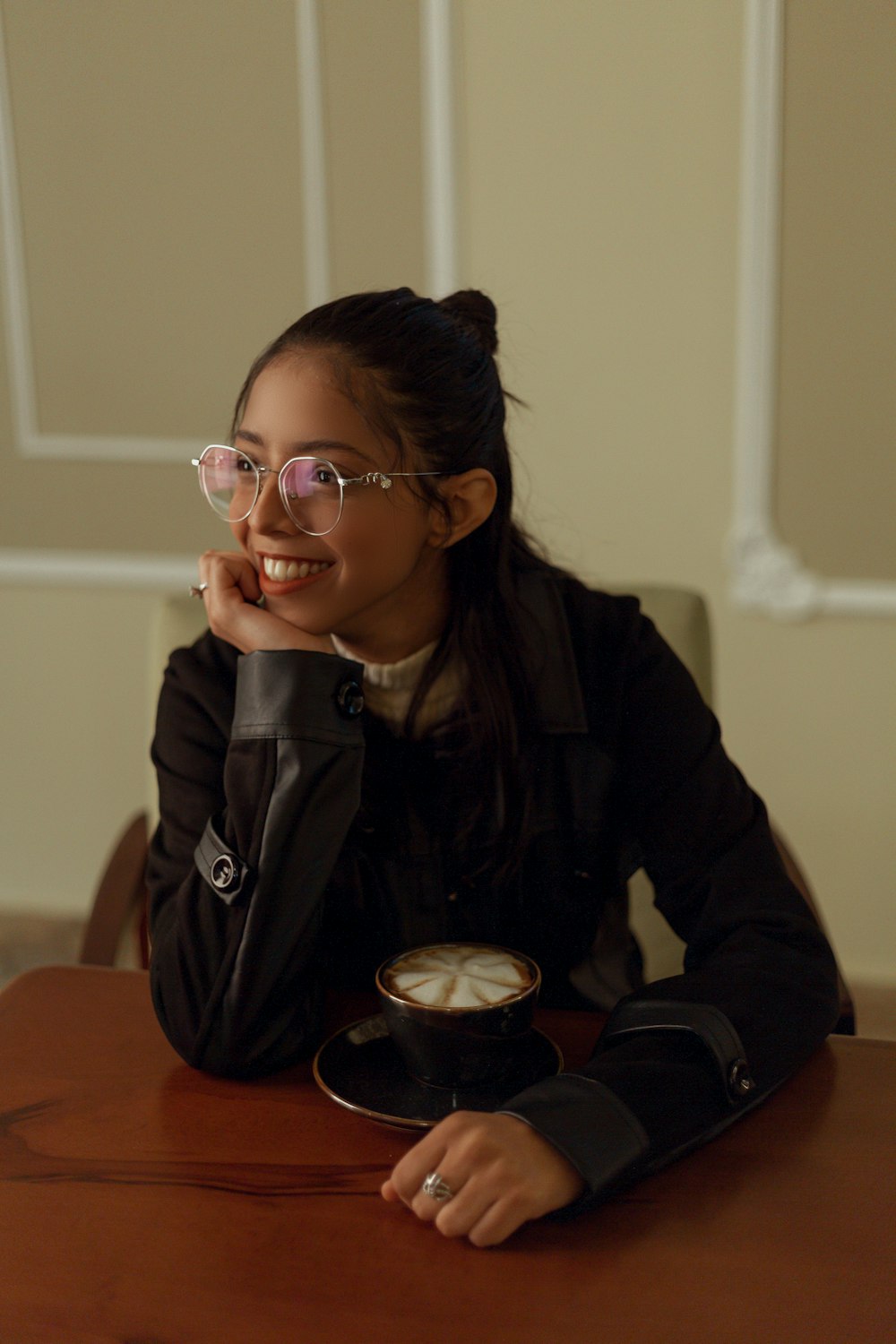 a woman sitting at a table with a cup of coffee