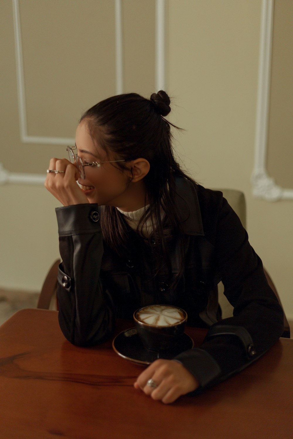 a woman sitting at a table with a cup of coffee