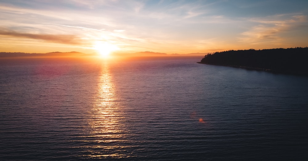 a sunset over a body of water with a small island in the distance