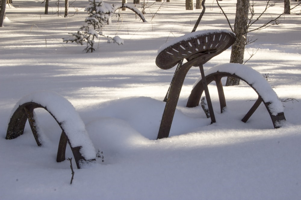 雪に覆われた森の真ん中に座っている木製のベンチ
