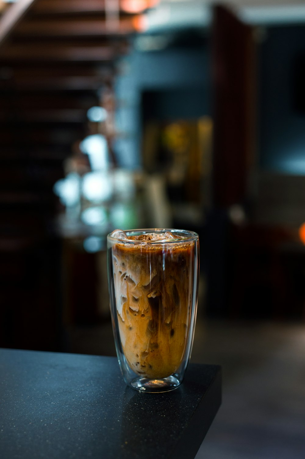 a glass of iced coffee sitting on top of a counter