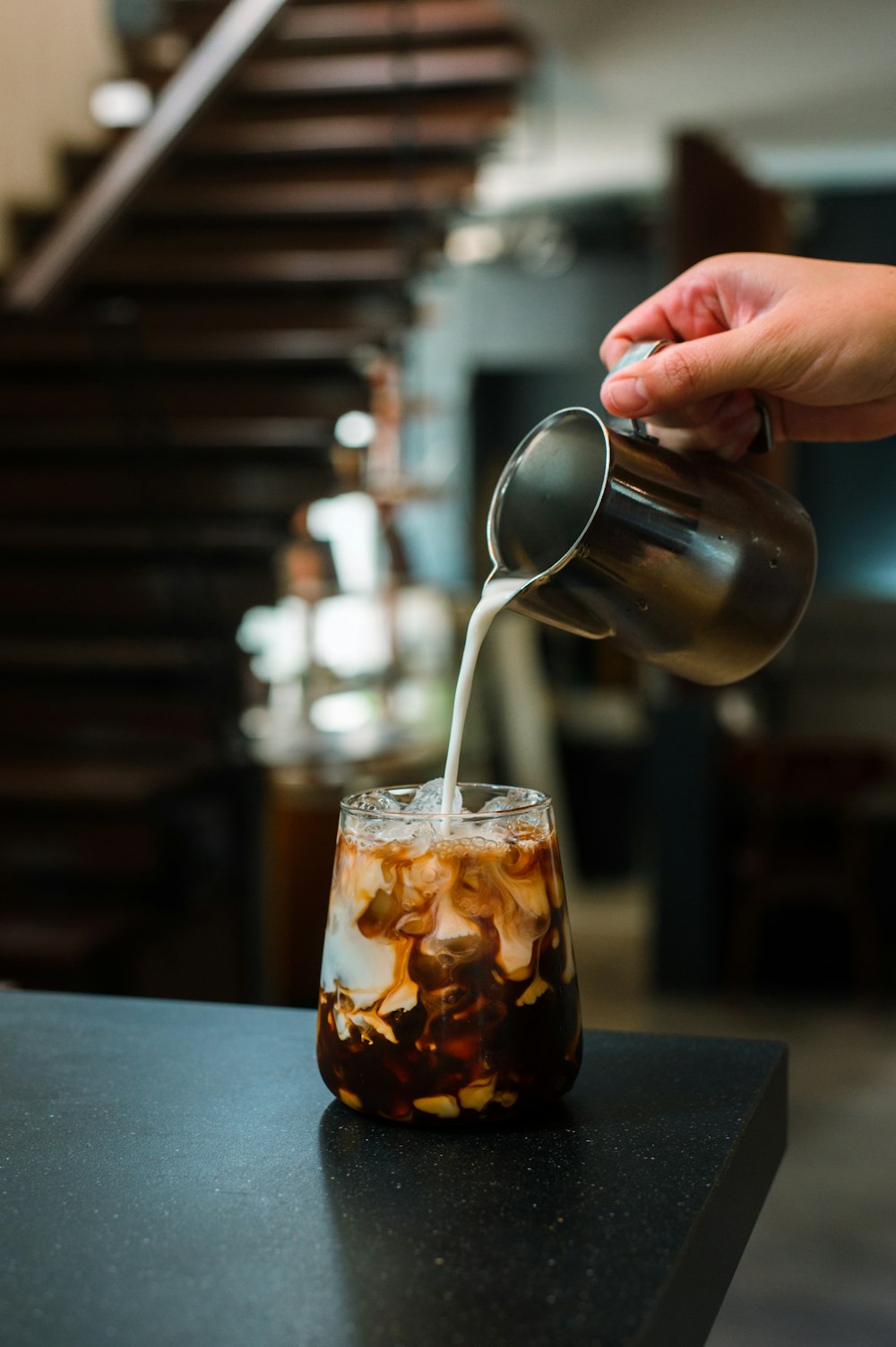 a person pouring a drink into a glass