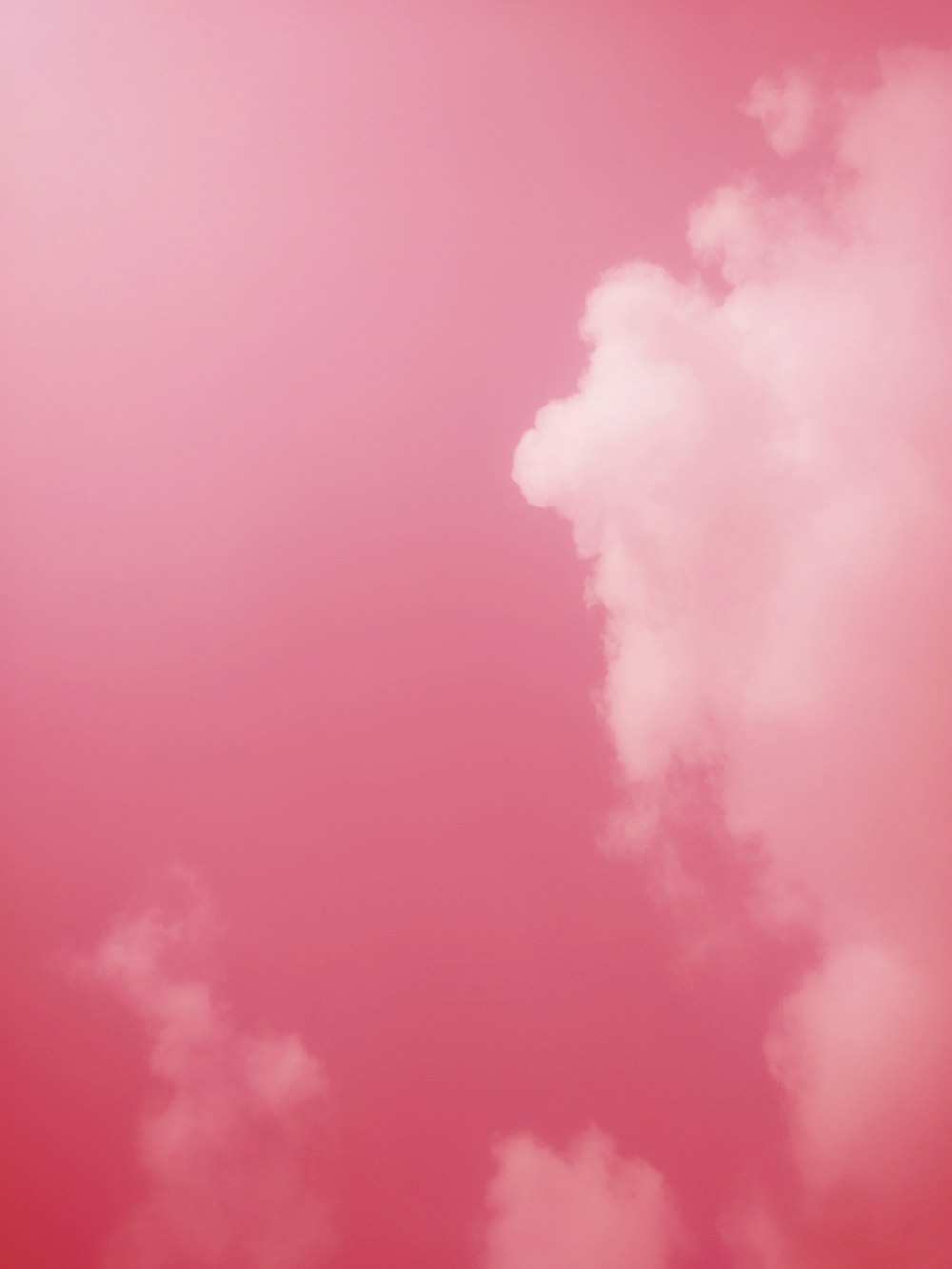 a plane flying through a pink sky with clouds