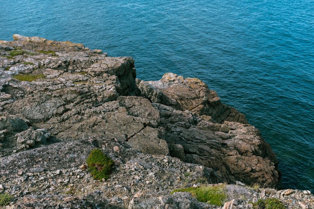 a person standing on top of a rocky cliff next to the ocean