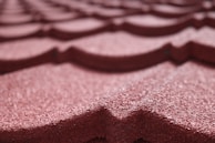 Close-up of a roof being painted with a durable, weather-resistant coating in deep red.
