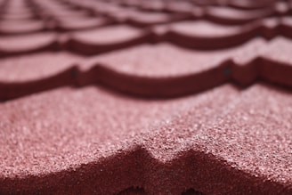 Close-up of a roof being painted with a durable, weather-resistant coating in deep red.
