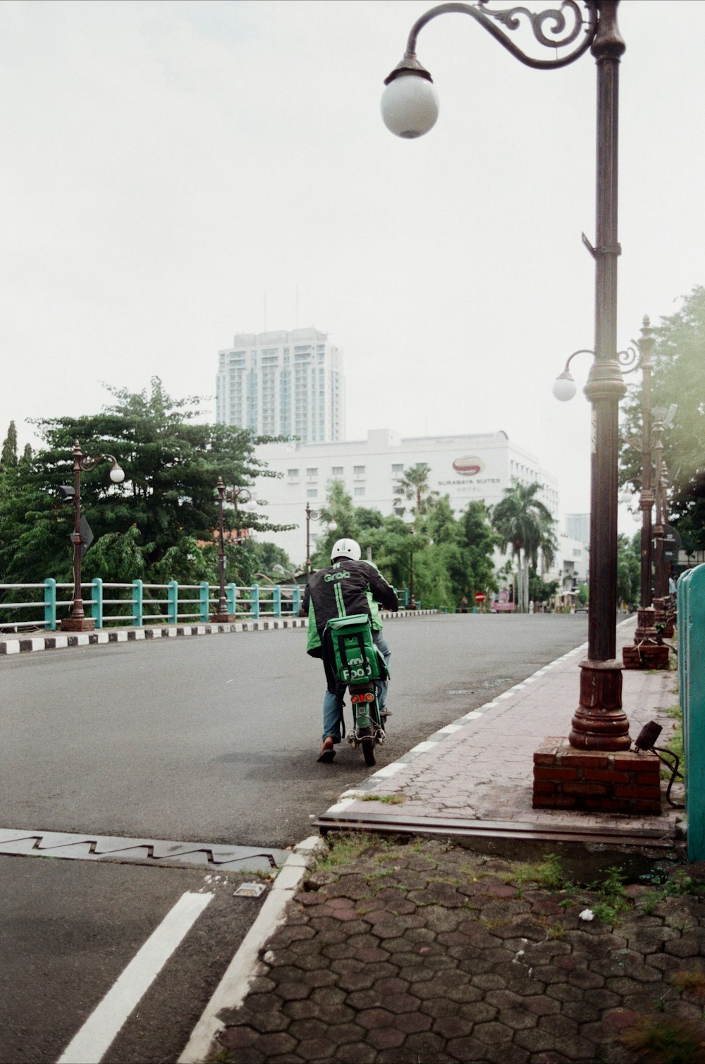 a man riding a motorcycle down a street next to a lamp post