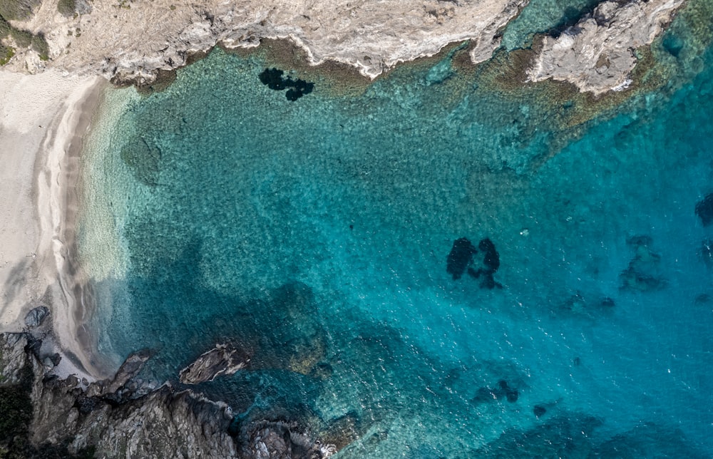 an aerial view of a beach with clear blue water