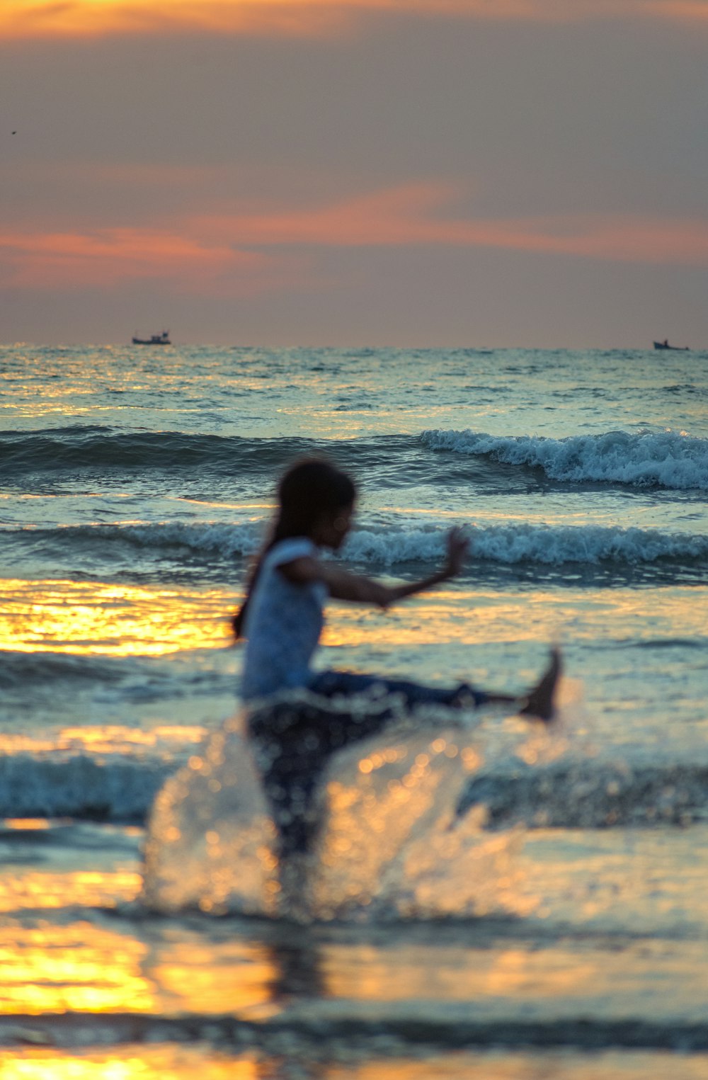a woman running into the ocean at sunset
