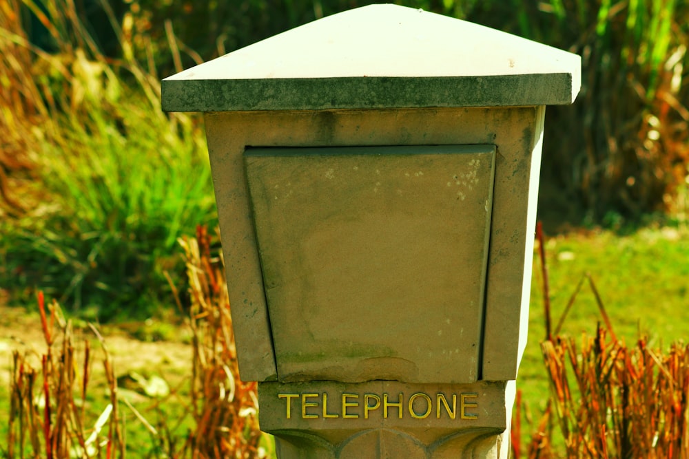 a telephone box sitting in the middle of a field