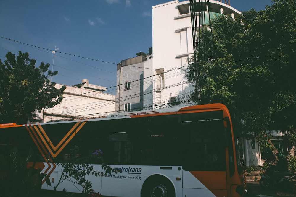 a white and orange bus parked in front of a building