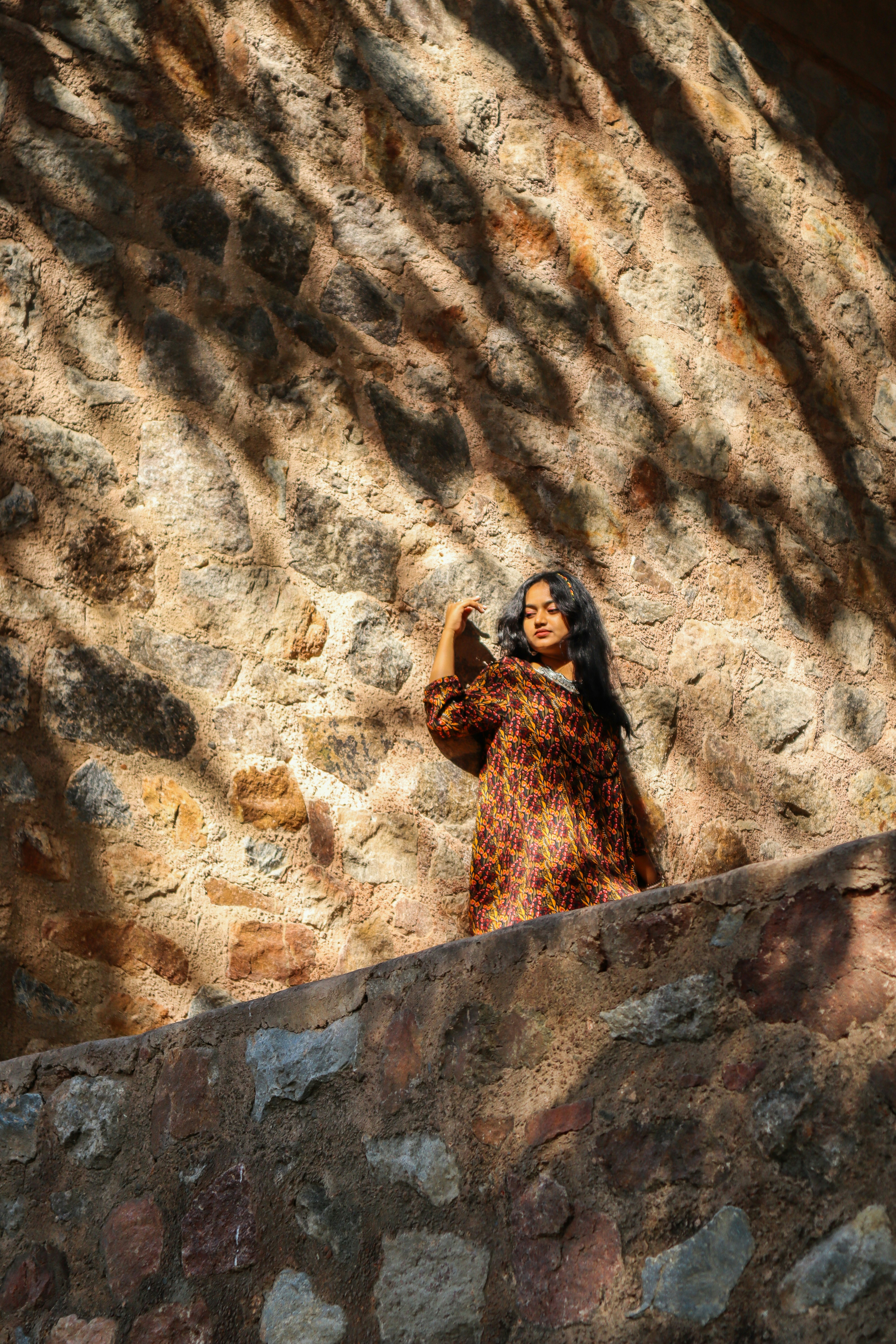A woman standing in front of a stone wall photo – Free Delhi Image on ...