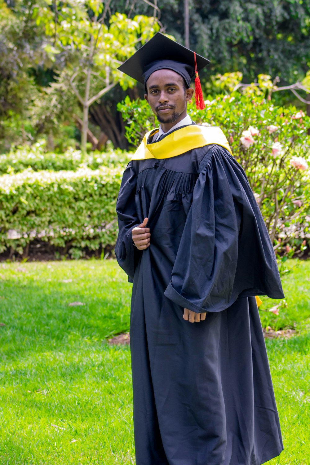 a man in a graduation gown standing in the grass