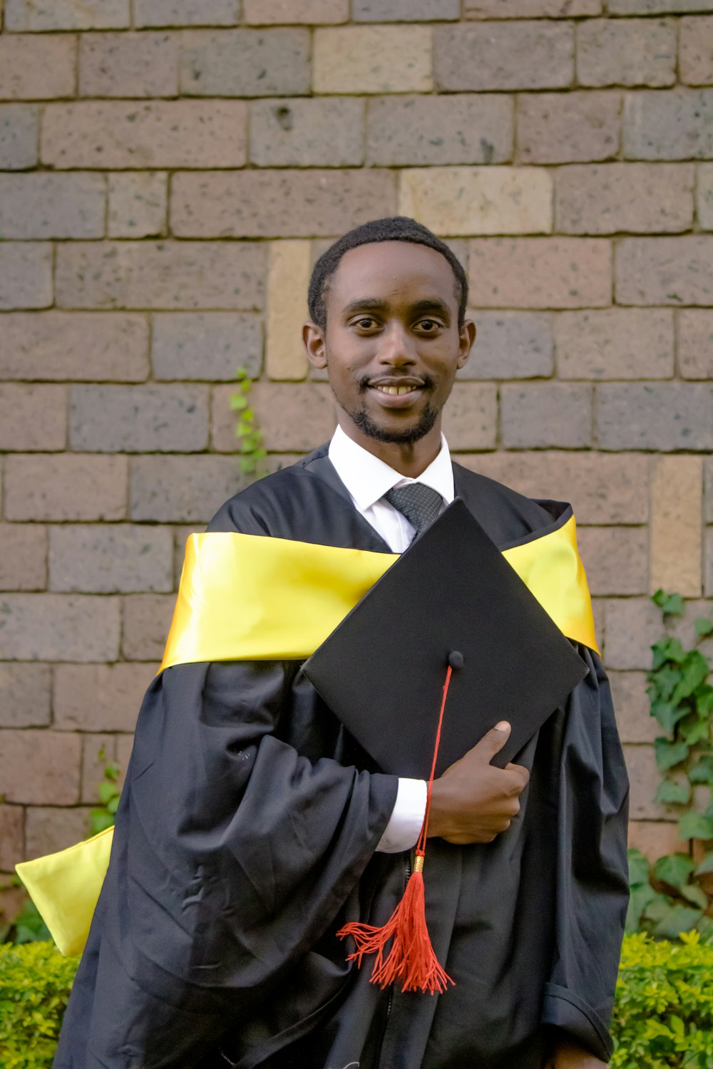 a man in a graduation gown holding his cap and gown