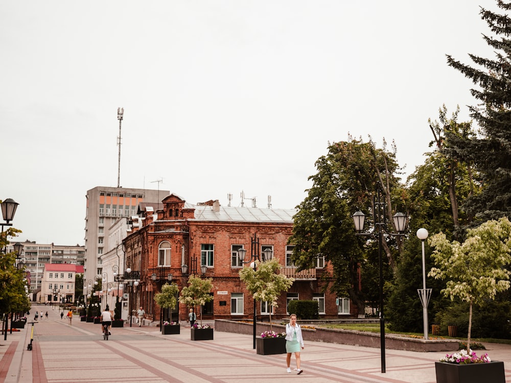 a woman walking down a street next to tall buildings