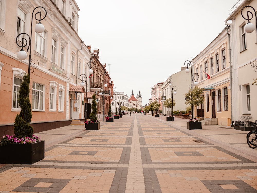 a city street lined with tall buildings and potted plants