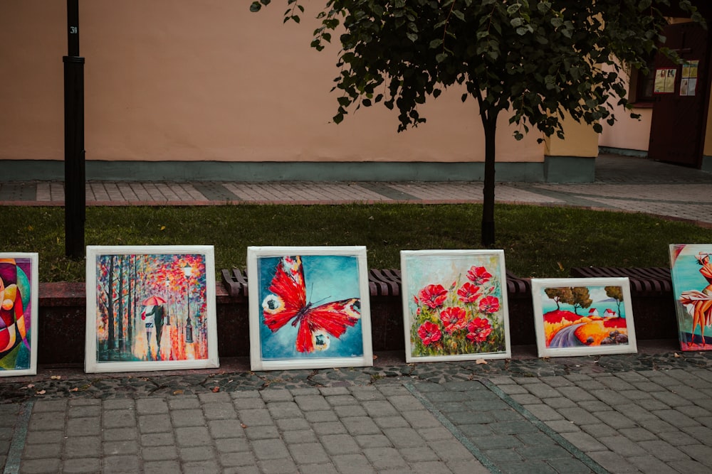 a row of paintings sitting on the side of a road