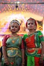Two companions dressed for a cultural event, smiling as they enter a grand venue.