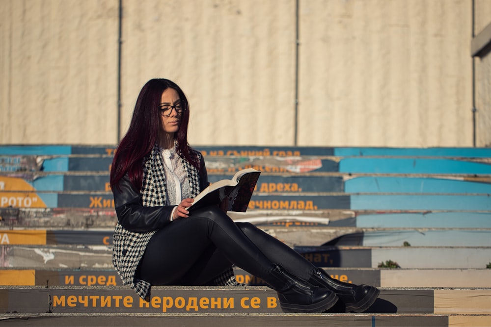 a woman sitting on the ground reading a book