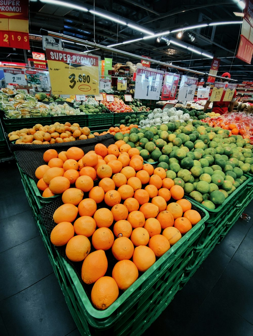 a produce section of a grocery store filled with oranges and melons