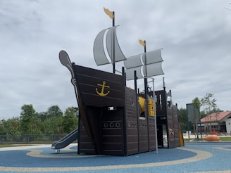 Parents enjoying a cup of coffee while watching their children sail the pirate boat in the play area.