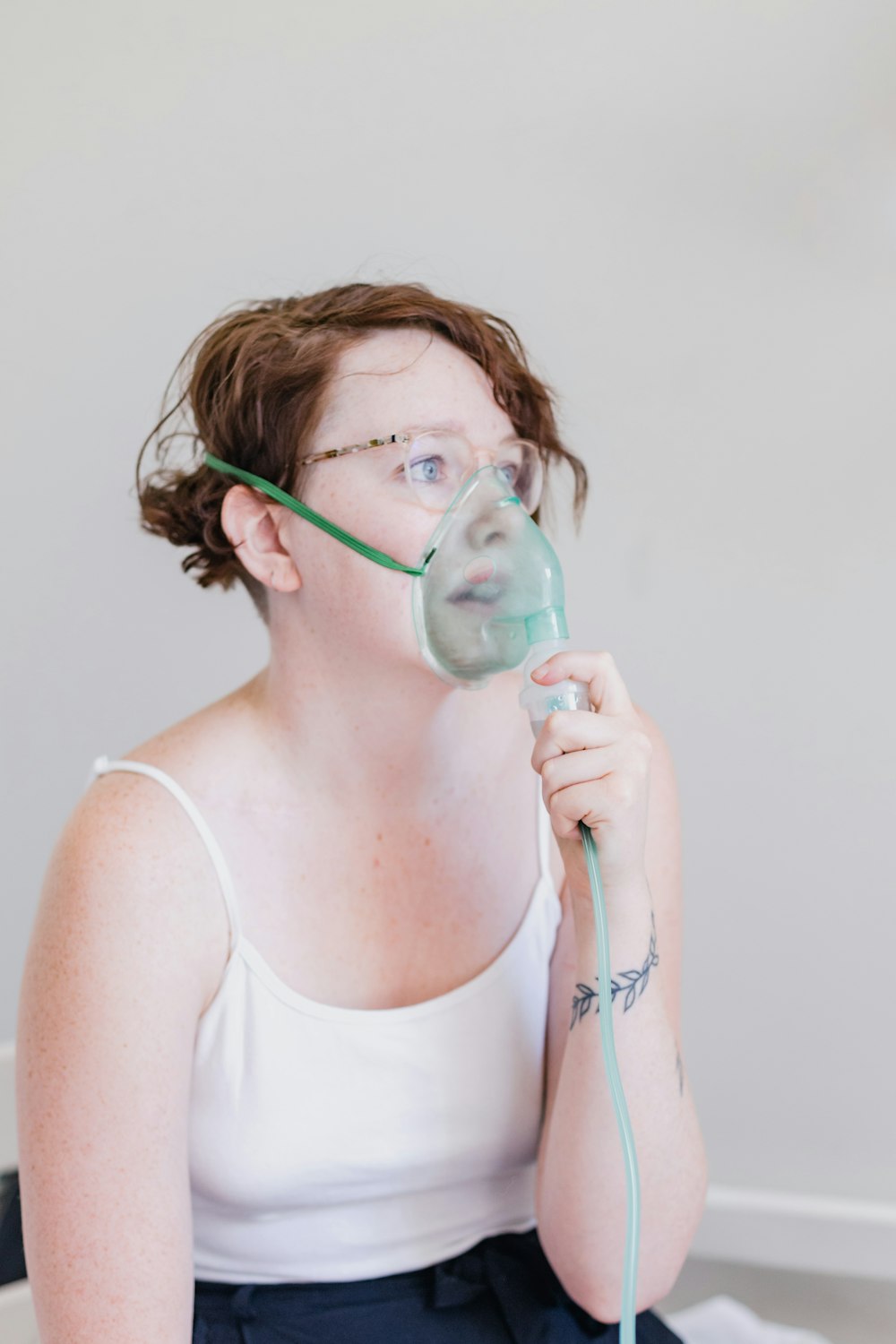 a woman sitting on a bed with a blow dryer in her mouth