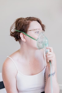 a woman in a white tank top with a mask on her face
