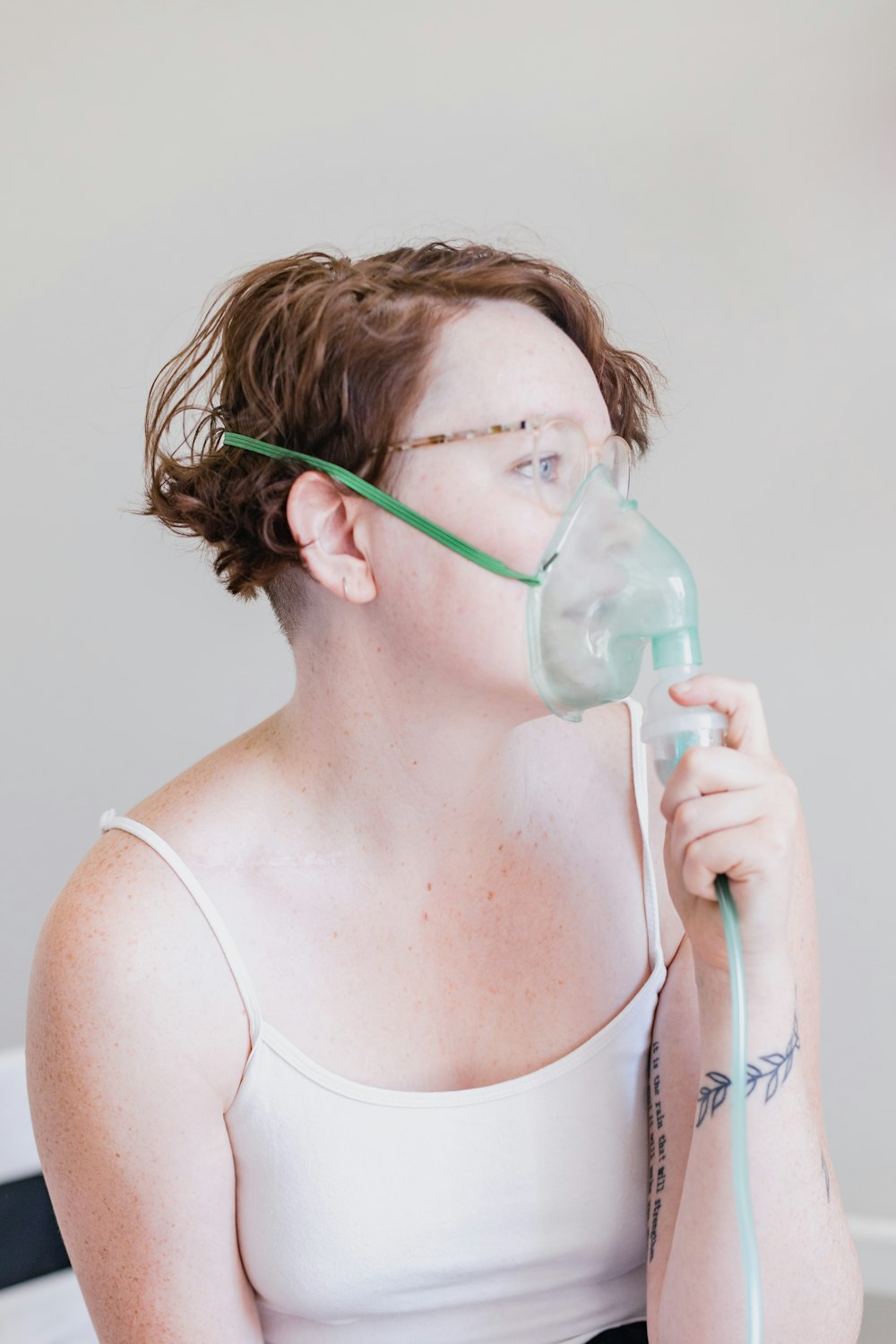 a woman in a white tank top with a mask on her face