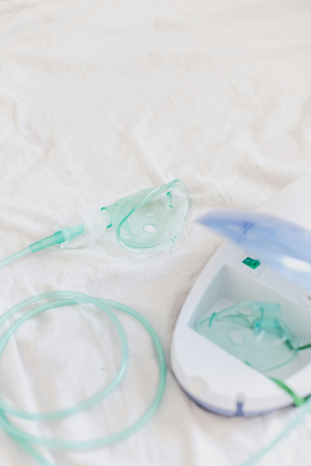 a white bed with a white sheet and a blue and green device on it