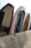 Several boats are placed vertically against a concrete barrier, with visible wear and paint peeling from their surfaces. The boats are lined up closely, showcasing various colors and the ropes hanging loosely.
