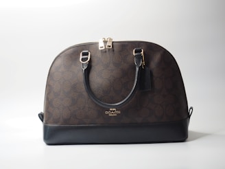 a brown and black handbag sitting on top of a white table