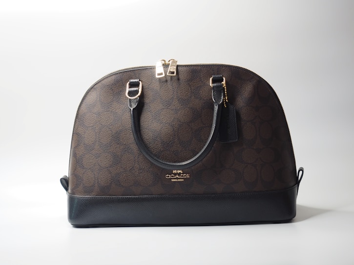 a brown and black handbag sitting on top of a white table