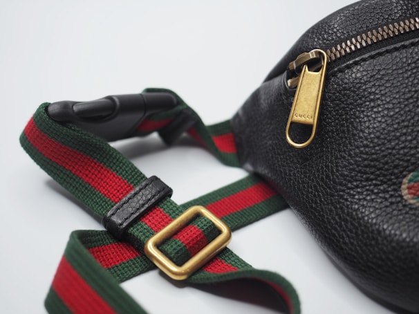 a black purse with a red, green and red striped strap