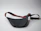 Close-up of a stylish mini waist pack resting on a wooden bench with a cityscape in the background.