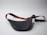 A black leather waist bag with a contrasting strap featuring red and green stripes is shown. The strap includes an adjustable buckle and a gold metal clip. The bag is laid out on a plain light gray surface, creating a minimalistic backdrop.