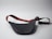 A black leather waist bag with a contrasting strap featuring red and green stripes is shown. The strap includes an adjustable buckle and a gold metal clip. The bag is laid out on a plain light gray surface, creating a minimalistic backdrop.