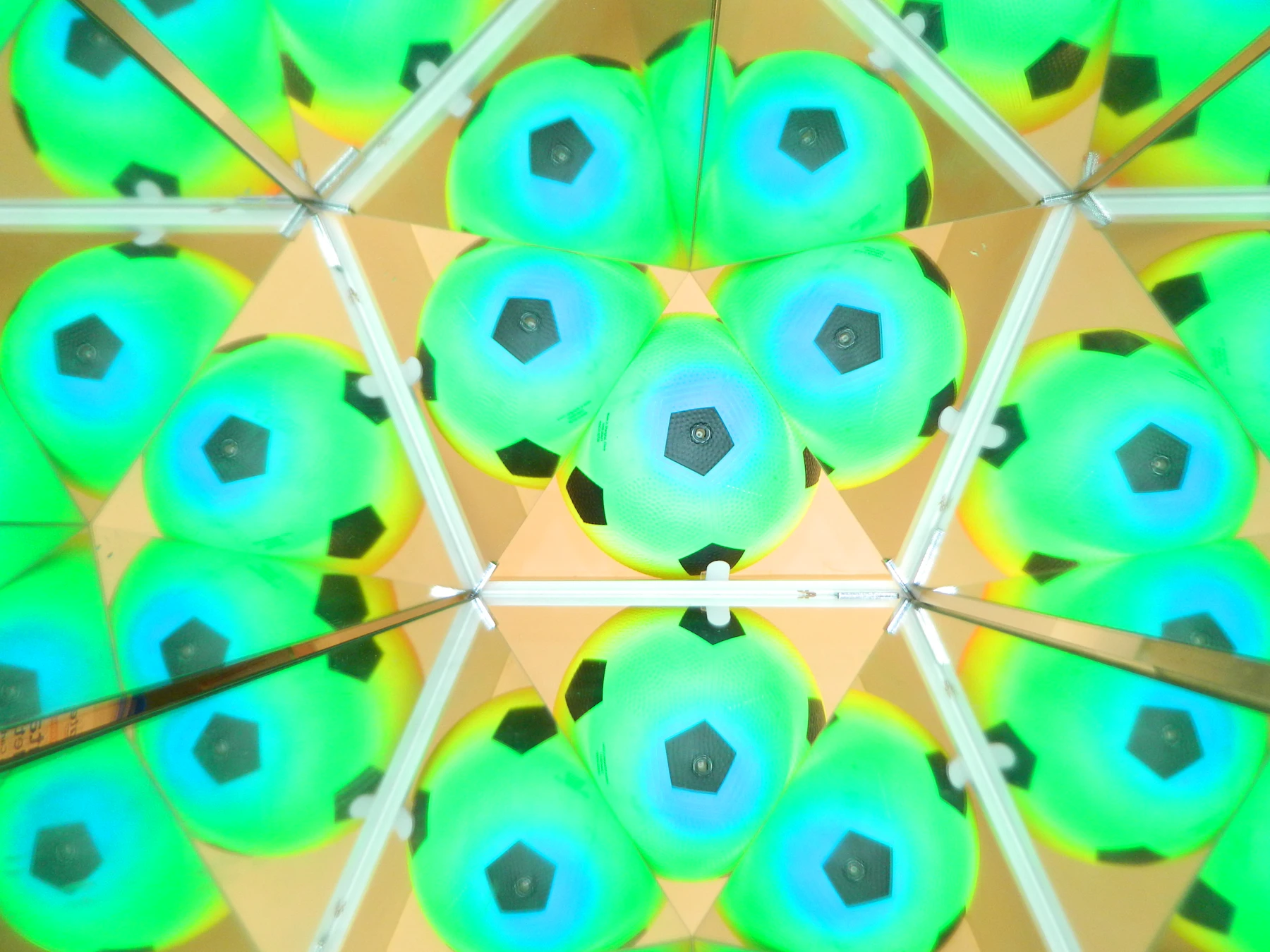 The view down a three-mirror tube: green and blue balls repeated in triangles, with the seams where the mirrors meet showing as bright lines