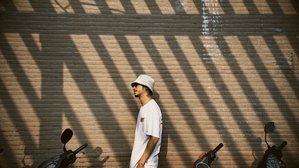 a man standing in front of a brick wall