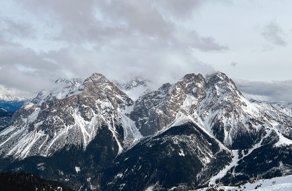 a snow covered mountain range under a cloudy sky