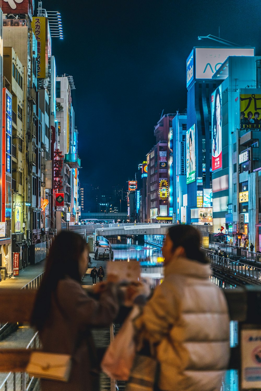 two people sitting on a bench in a city at night