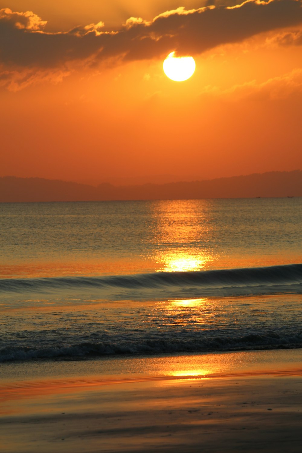 the sun is setting over the ocean on a cloudy day