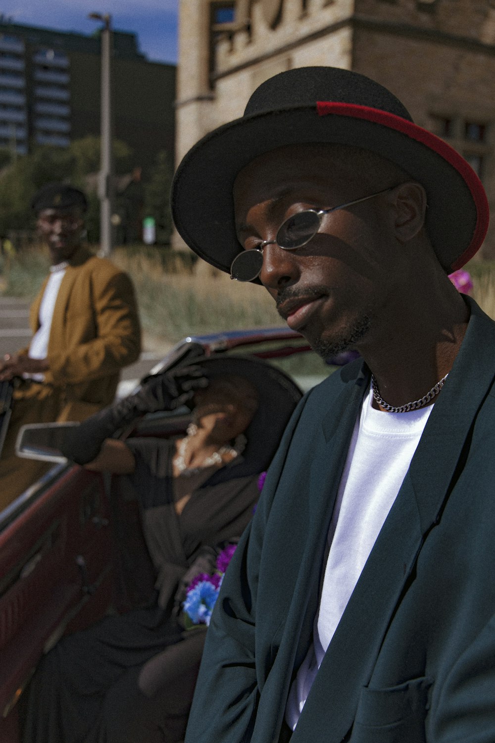 a man in a suit and hat sitting in a car