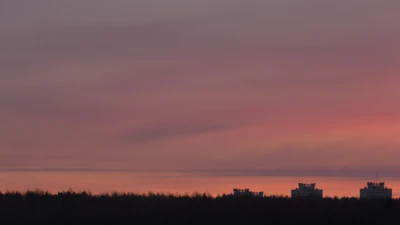 Sunset view over a quiet city skyline, with warm orange and pink hues.