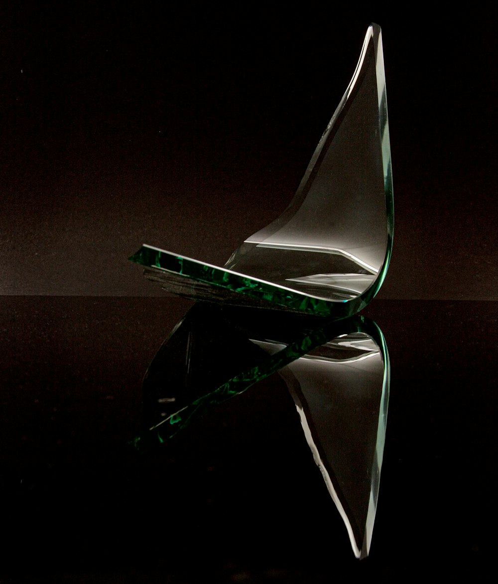 a glass sailboat sitting on top of a black surface
