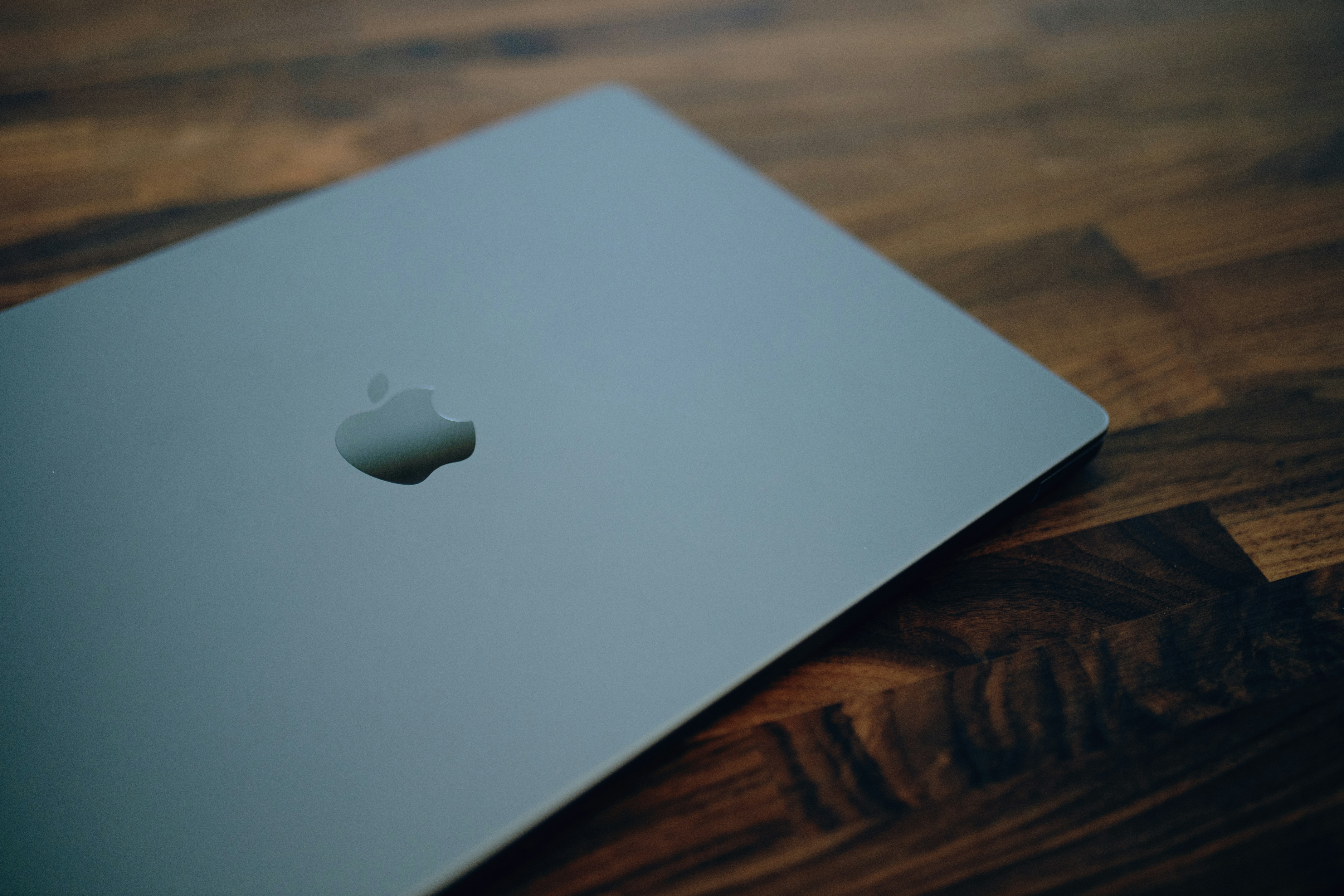 an apple laptop sitting on top of a wooden table