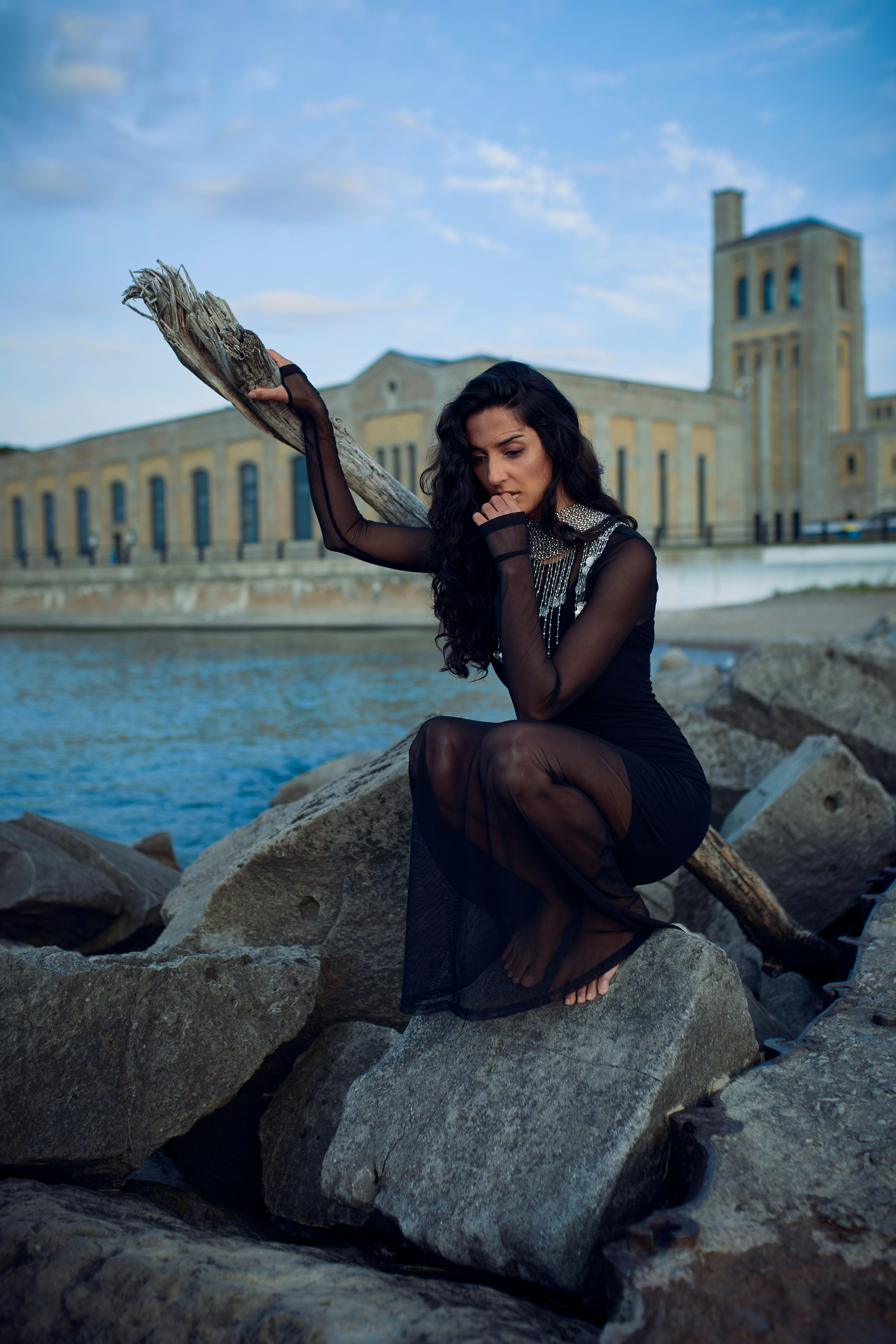 a woman sitting on a rock next to a body of water